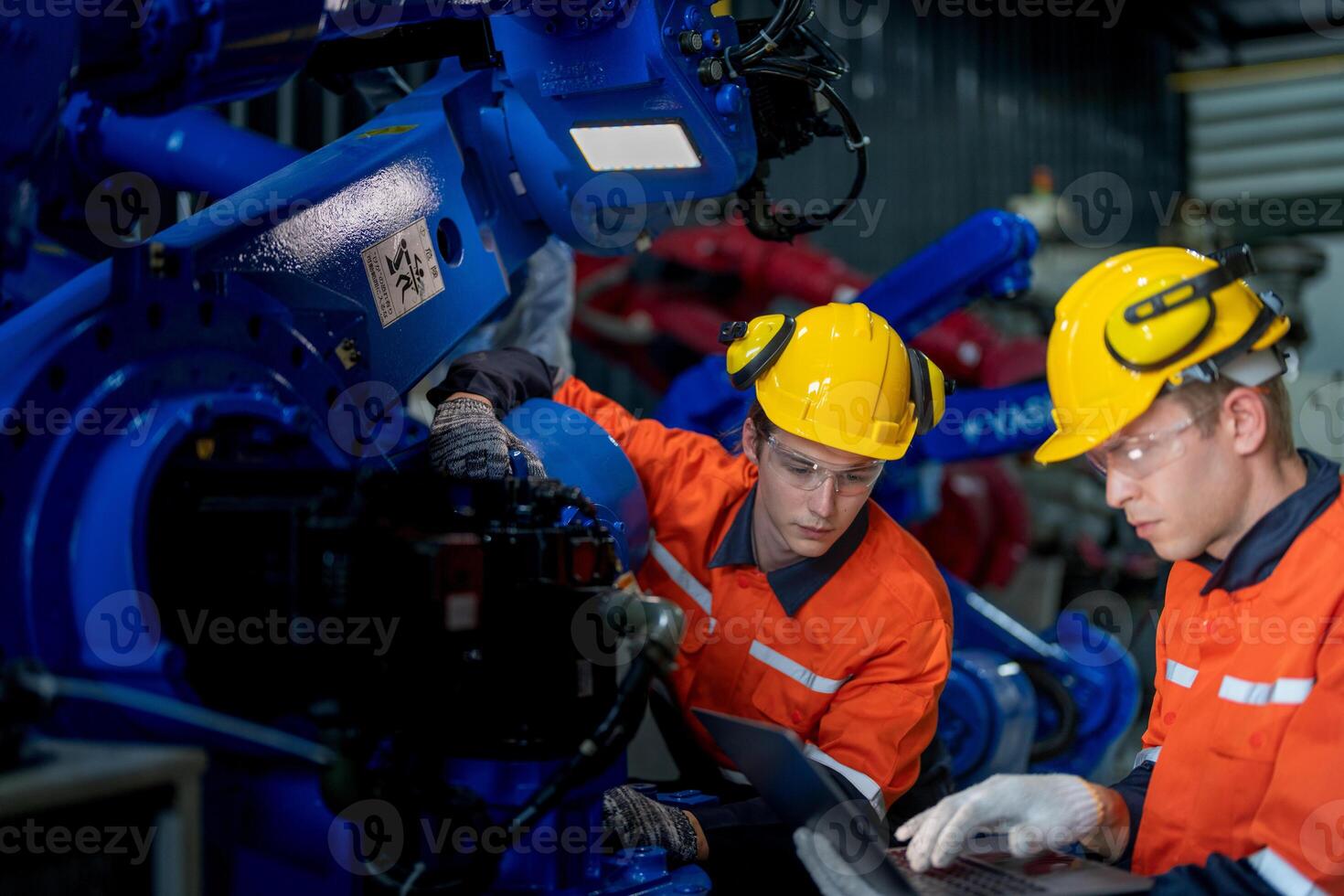 Fabrik Ingenieure inspizieren auf Maschine mit Clever Tablette. Arbeiter funktioniert beim schwer Maschine Roboter Arm. das Schweißen Maschine mit ein Fernbedienung System im ein industriell Fabrik. künstlich Intelligenz Konzept. foto