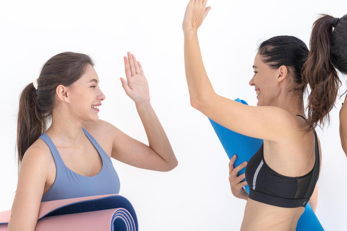 Gruppe von glücklich sportlich Frauen reden mit Körper stilvoll Sportbekleidung halten persönlich Teppiche beugte sich vor auf ein Weiß Hintergrund. warten zum Yoga Klasse oder Körper Gewicht Klasse. gesund Lebensstil und Wellness foto