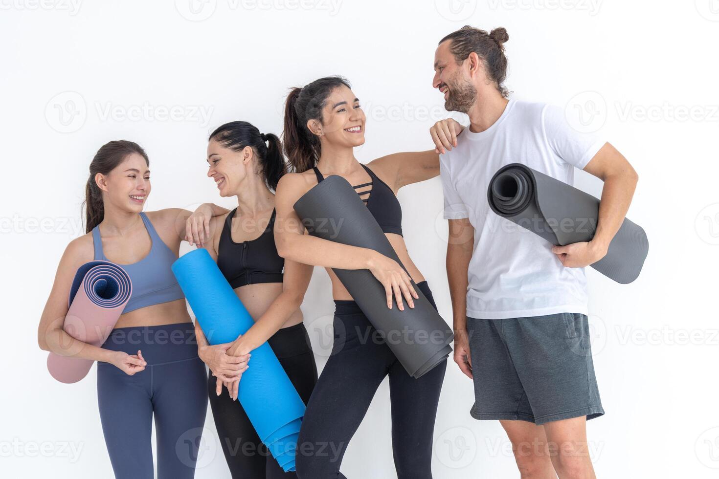 Gruppe von glücklich sportlich Frauen und Kerl tragen Körper stilvoll Sportbekleidung halten persönlich Teppiche beugte sich vor auf ein Weiß Hintergrund. warten zum Yoga Klasse oder Körper Gewicht Klasse. gesund Lebensstil und Wellness foto