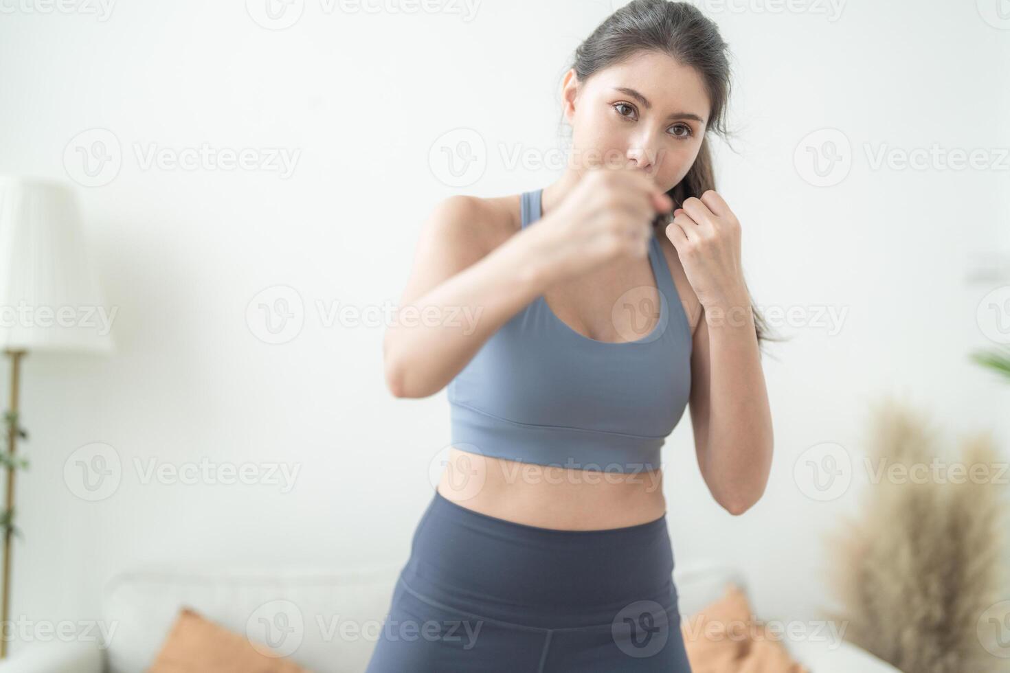 attraktiv und stark Frau Dehnen Vor Fitness beim Innen- Haus. gesund Lebensstil. Frau warm oben durch Boxen im das Luft. jung weiblich mit schlank Körper Stanzen Boxen Beinarbeit Cardio Übung. foto