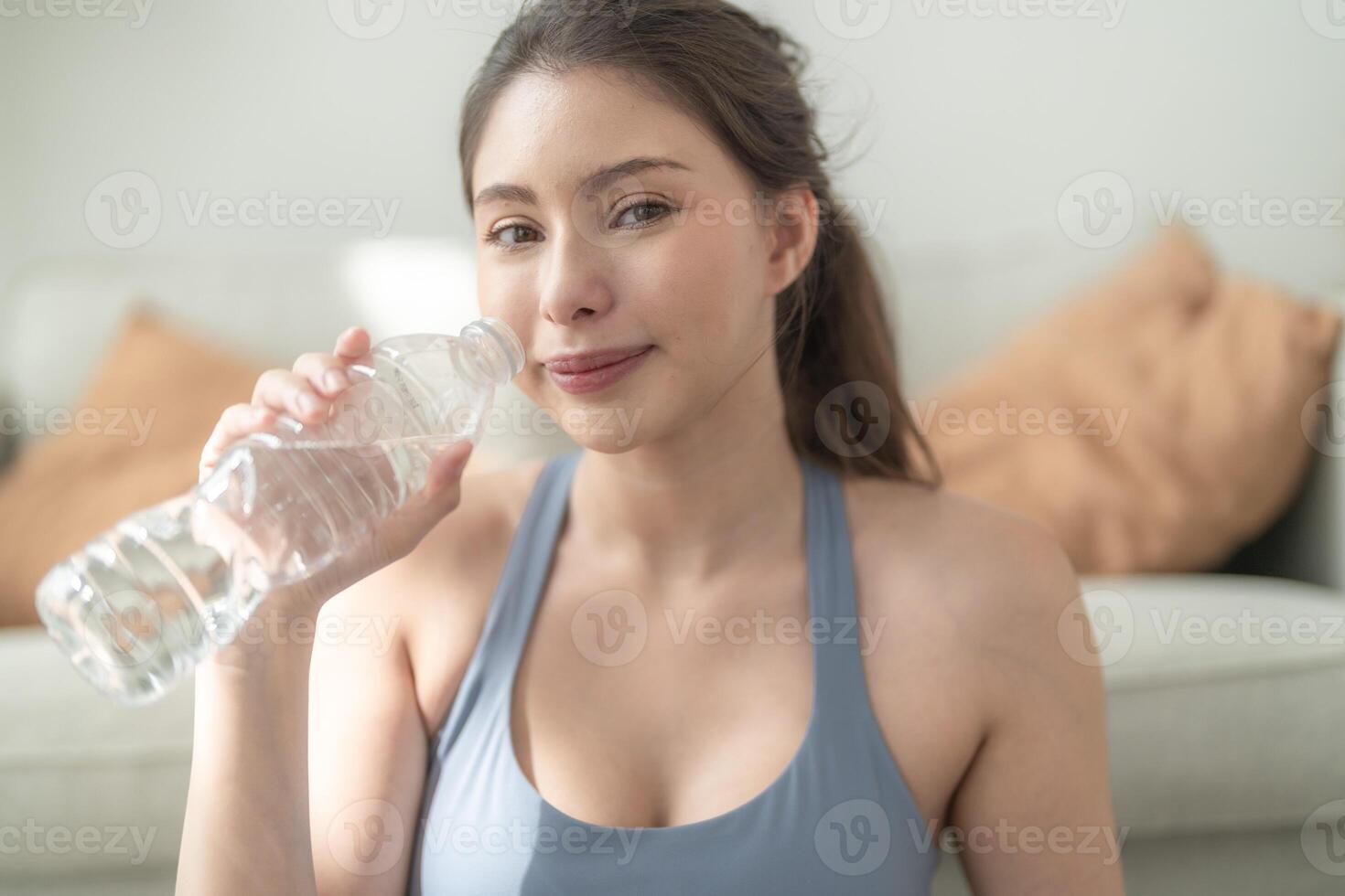 schließen oben von jung Gesicht kaukasisch Fitness Frau tragen Sport Kleider Ausbildung Innen- Trinken frisch Wasser. gesund Lebensstil und Wohlbefinden. foto