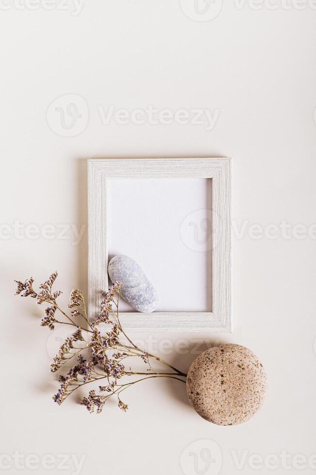 Komposition von ein leeren Foto rahmen, getrocknet Blumen und Steine auf ein Licht Hintergrund oben und Vertikale