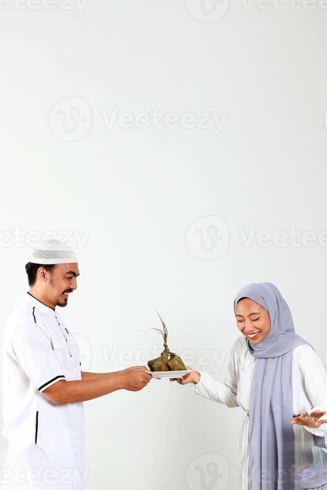 asiatisch Muslim weiblich und männlich halten Weiß Teller mit Ketupat zum eid Mubarak Feier foto