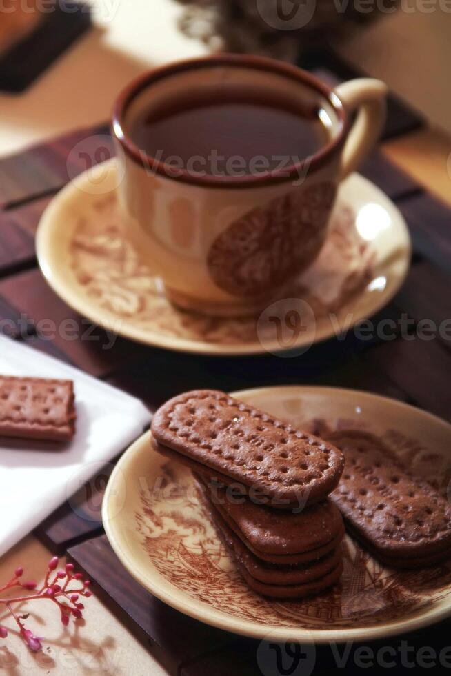 Tasse von Tee und Schokolade Kekse auf hölzern Tisch, Nahansicht foto