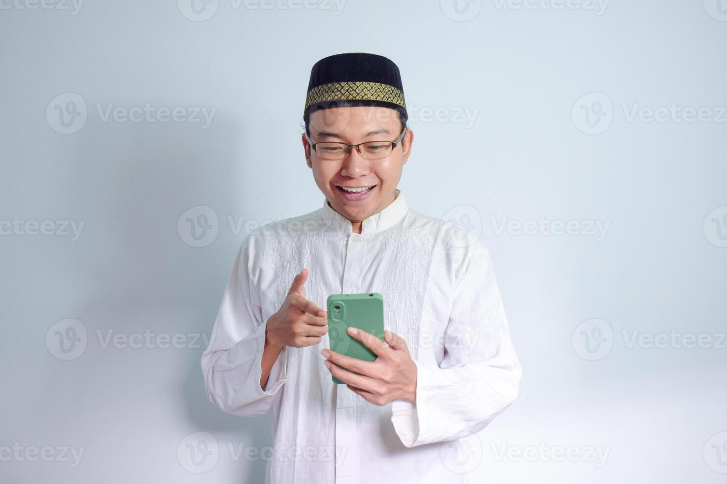 asiatisch Muslim Mann tragen Brille und Weiß Stoff zeigen Telefon Pose zum Ramadhan und eid al fitr. isoliert Weiß Hintergrund foto