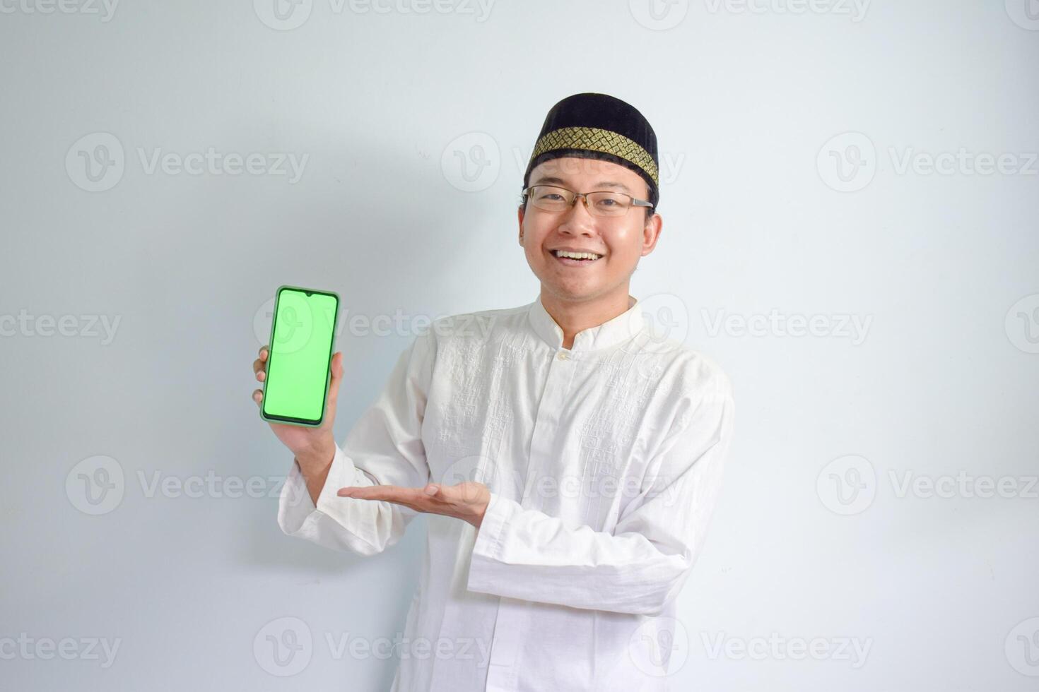 asiatisch Muslim Mann tragen Brille und Weiß Stoff zeigen Telefon Pose zum Ramadhan und eid al fitr. isoliert Weiß Hintergrund foto