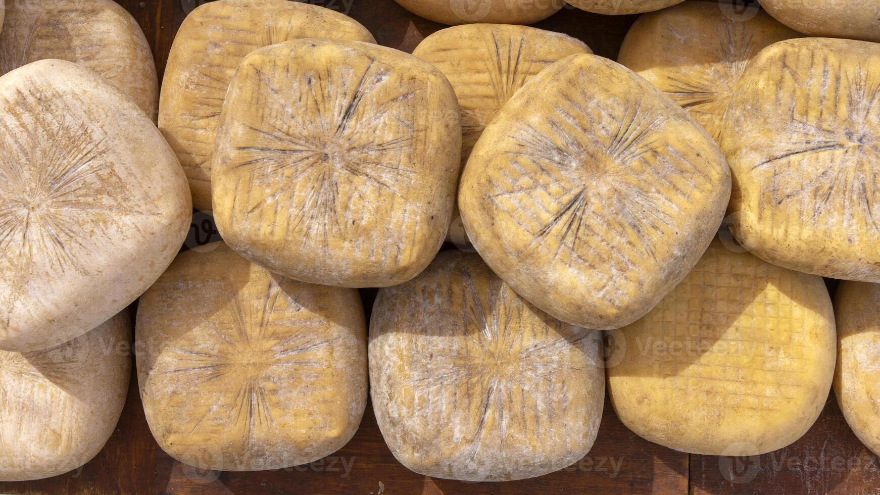 handwerklich Käse Räder gestapelt beim ein rustikal Markt Stall foto