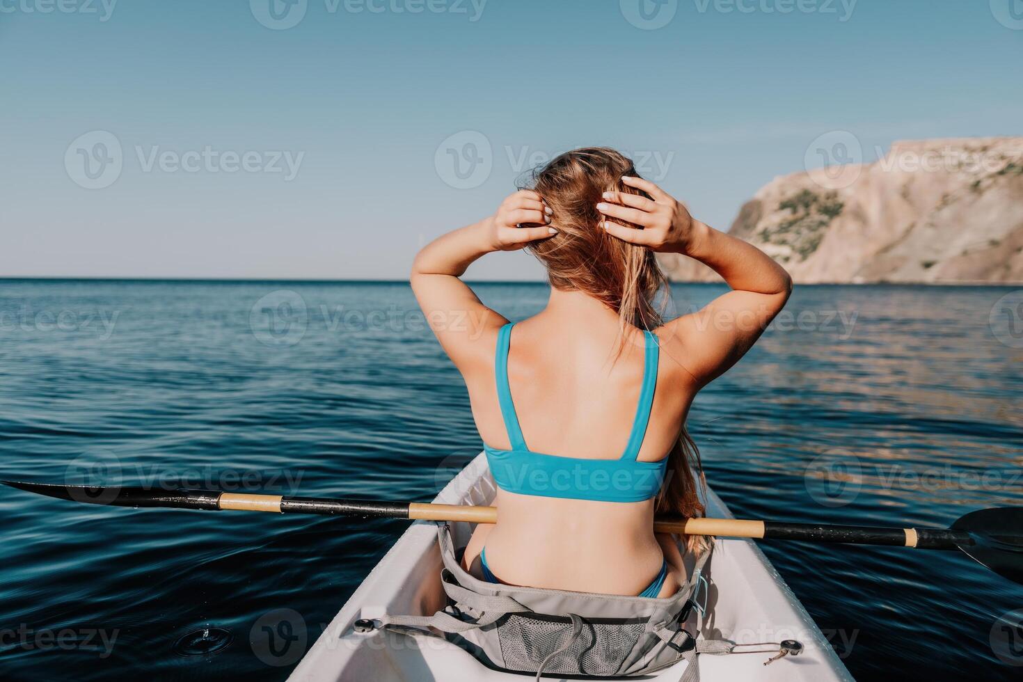 Frau im Kajak zurück Sicht. glücklich jung Frau mit lange Haar schwebend im Kajak auf Ruhe Meer. Sommer- Urlaub Ferien und heiter weiblich Menschen entspannend haben Spaß auf das Boot. foto