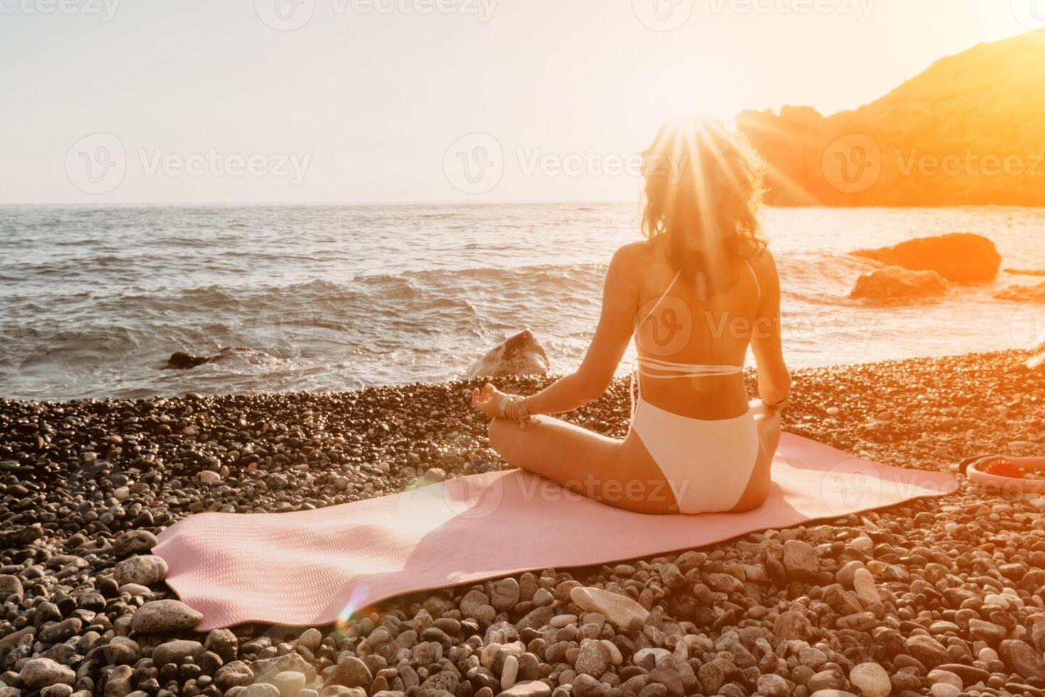 Frau Meer Yoga. glücklich Frau im Weiß Badeanzug und Boho Stil Armbänder üben draußen auf Yoga Matte durch Meer auf Sonnenuntergang. Frauen Yoga Fitness Routine. gesund Lebensstil, Harmonie und Meditation foto