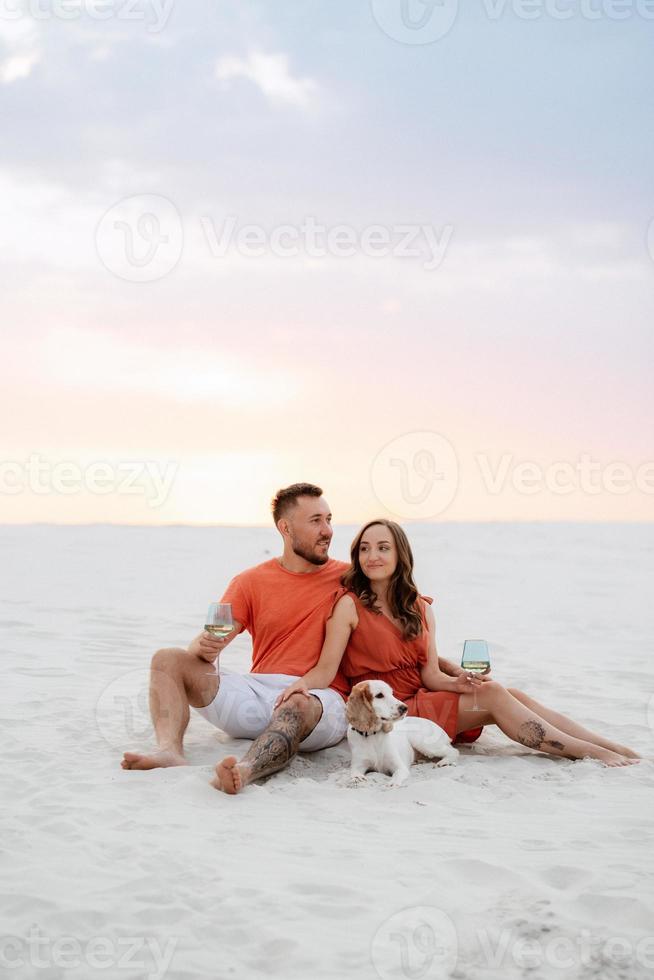 junges Paar in orangefarbener Kleidung mit Hund foto