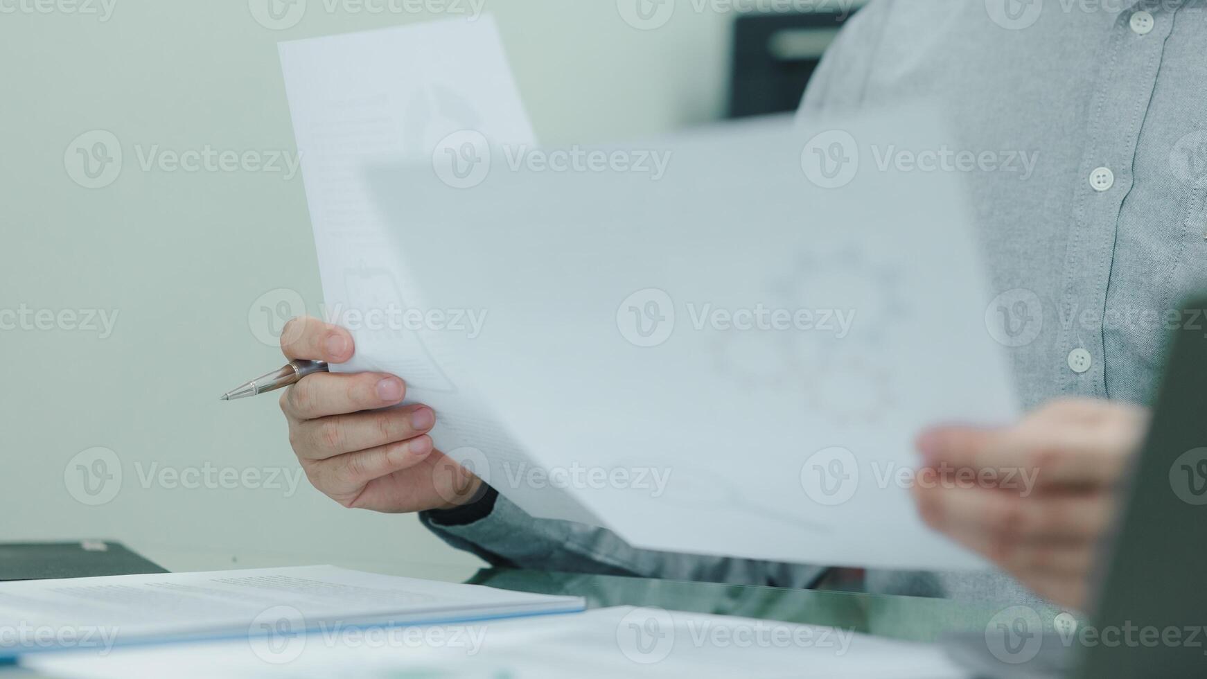 ein Geschäftsperson ist halten ein Stück von Papier mit ein Stift im ihr Hand. das Papier hat ein Diagramm von Getriebe auf Es. das Geschäftsmann erscheint zu Sein konzentriert auf das Graph foto