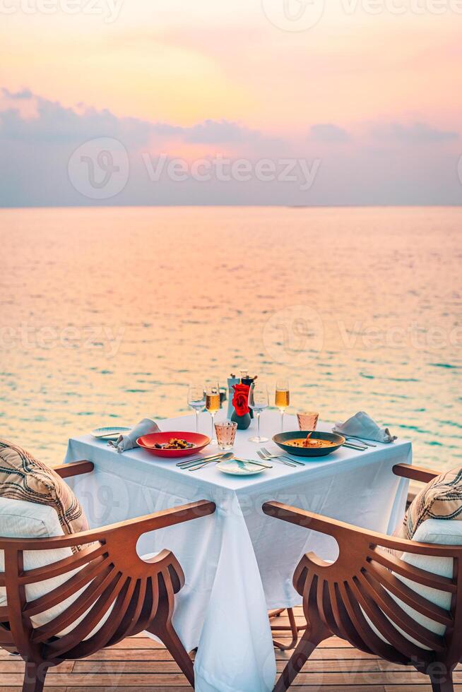 Seelandschaft Aussicht unter Sonnenuntergang Licht mit Essen Tabelle mit Unendlichkeit Schwimmbad um. romantisch still Flucht zum zwei, Paar Konzept. Stühle, Essen und Romantik. Luxus Ziel Essen, Flitterwochen Vorlage foto