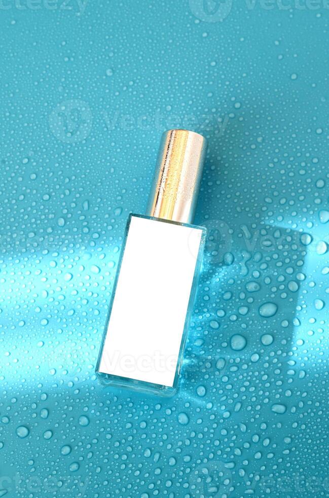 Parfüm Flasche mit spotten oben auf Blau Hintergrund mit schwer Licht und Wasser Tropfen. mit Schatten eben legen, oben Aussicht foto