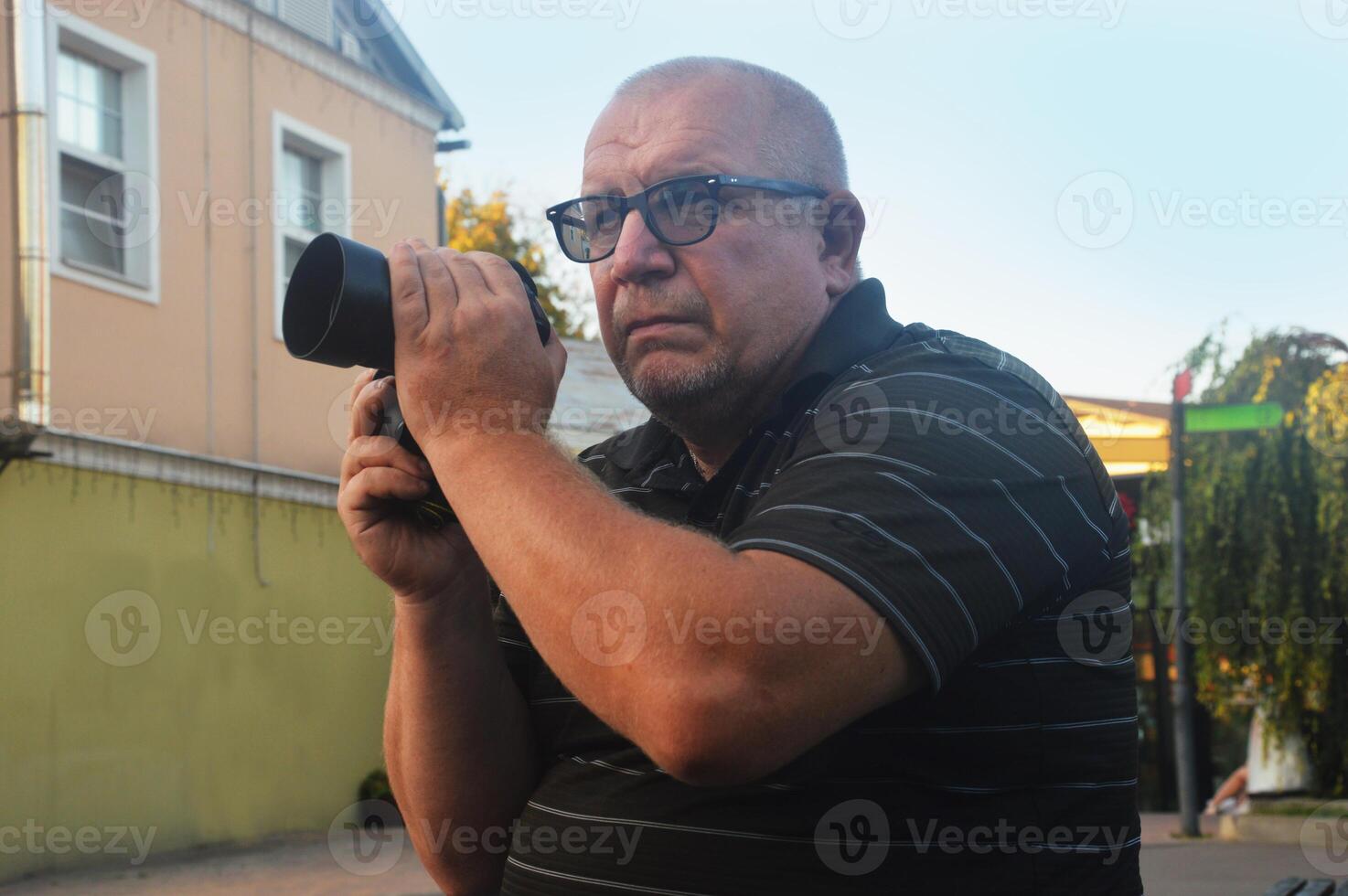 kaukasisch Mann Fotograf mit ein modern Kamera auf ein Stadt Straße. das Schießen Verfahren. foto