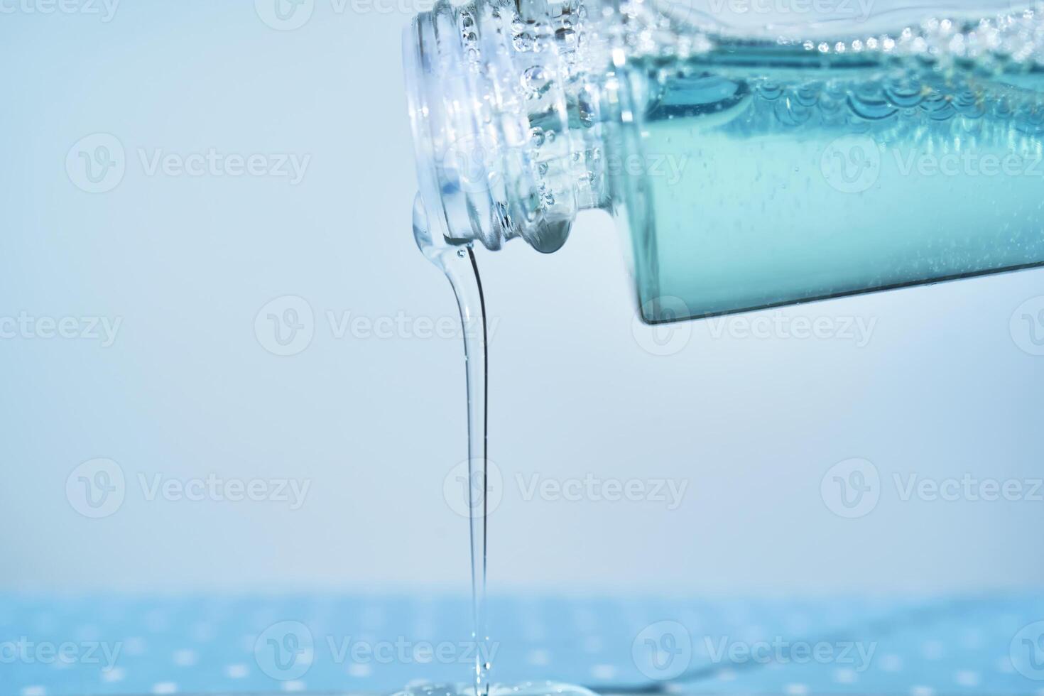 kosmetisch Flasche von welche Serum ist Gießen auf ein Blau Hintergrund. foto