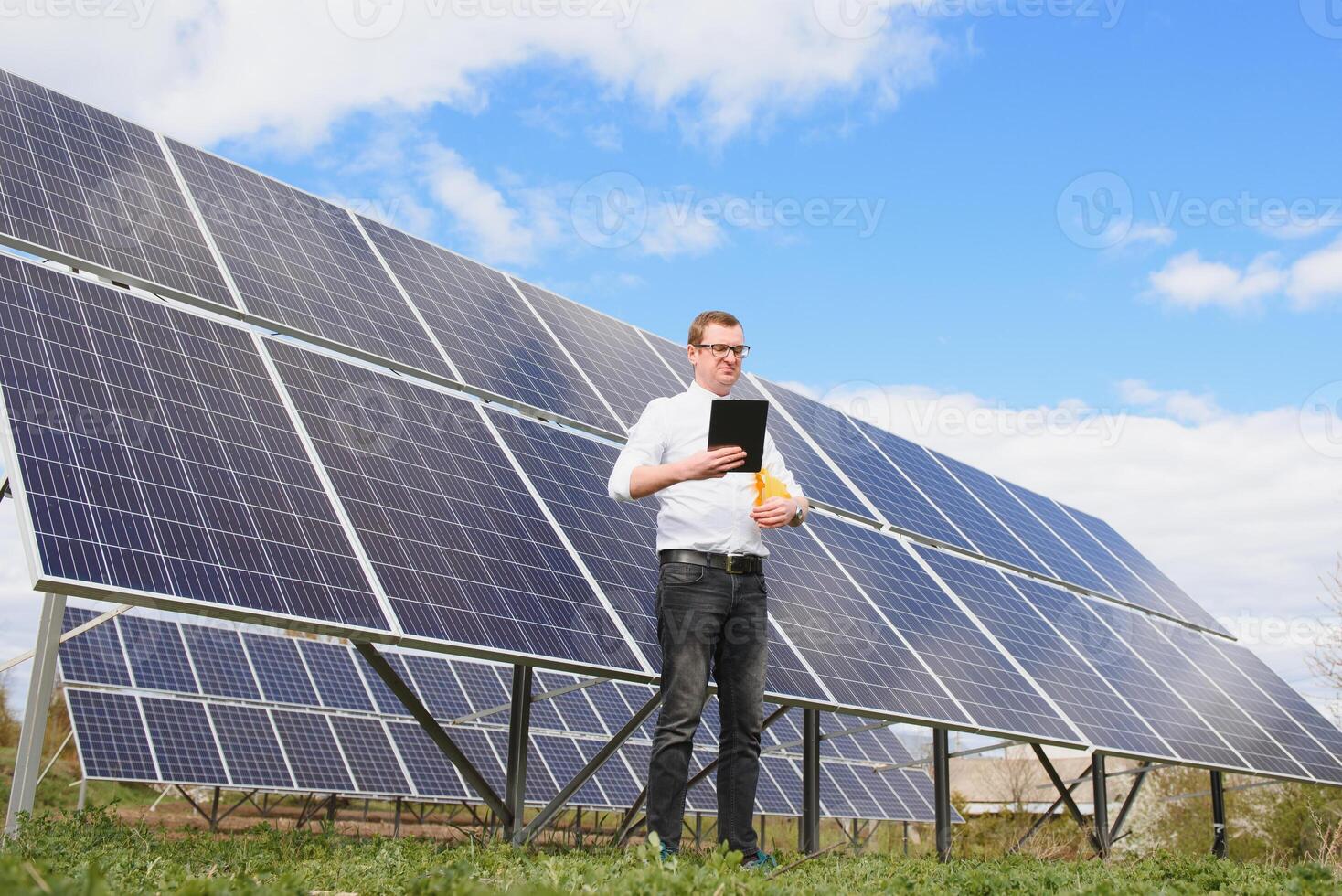 Solar- Energie. jung Geschäft Mann im ein Weiß Hemd in der Nähe von das Solar- Paneele zu Leistung Pflanzen. foto