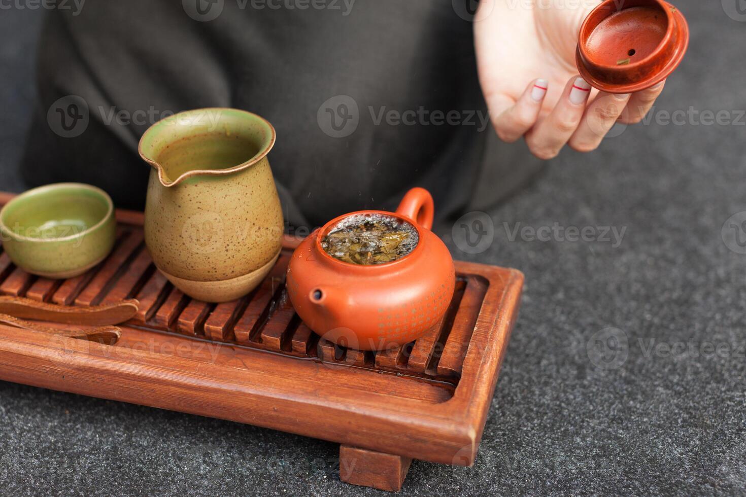 ein Mädchen im ein grau Leinen- Hemd arrangiert ein königlich Zeremonie, klassisch Zubehör zum ein Tee Zeremonie. Konzept von gesund Essen und traditionell Getränke foto