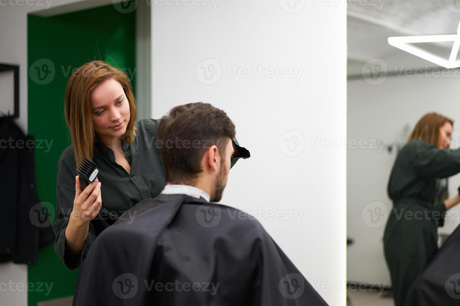 gut aussehend Blau Augen Mann Sitzung im Barbier Geschäft. Friseur Friseur Frau Schneiden seine Haar. weiblich Barbier. foto