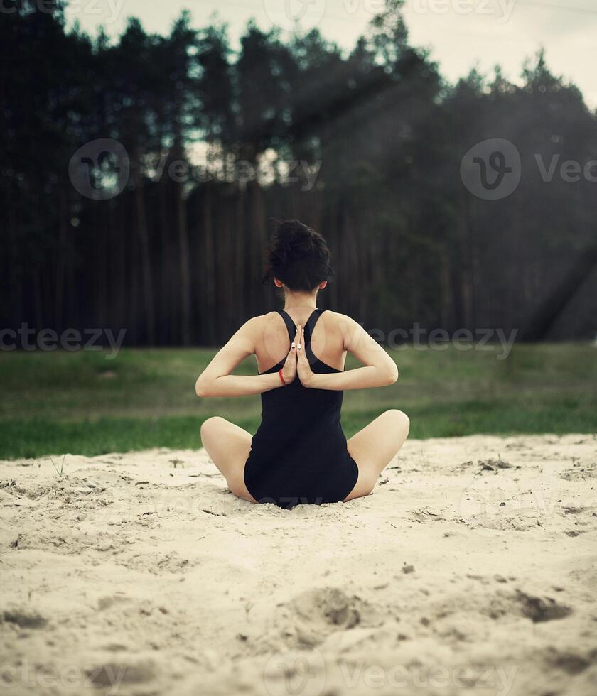 schön Mädchen ist beschäftigt, verlobt im Yoga im das Wald auf das Sand foto