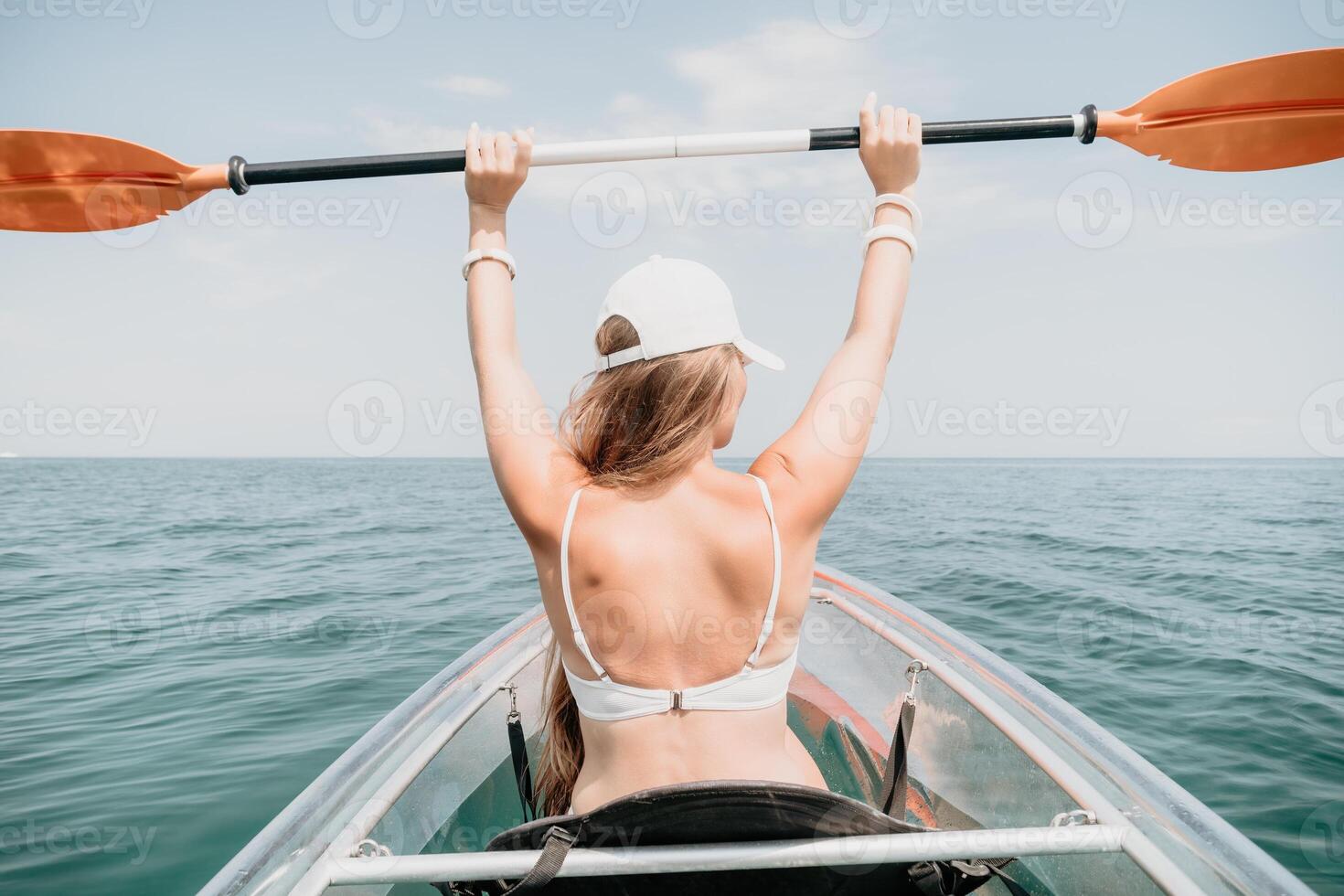 Frau im Kajak zurück Sicht. glücklich jung Frau mit lange Haar schwebend im transparent Kajak auf das Kristall klar Meer. Sommer- Urlaub Ferien und heiter weiblich Menschen entspannend haben Spaß auf das Boot foto