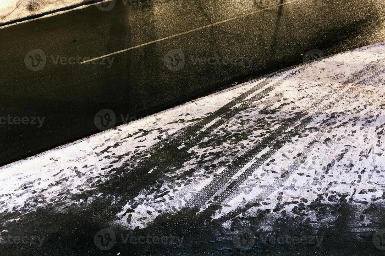 Pflaster mit Fußabdrücke im das Schnee Nächster zu das Straße foto