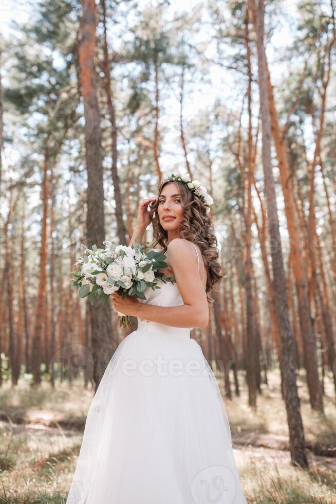 ein süß lockig Frau im ein Weiß Hochzeit Kleid mit ein Hochzeit Strauß und Kranz im ihr Haar Stehen zurück zu das Kamera im Natur. Konzept entkam Braut. nach vorne zu ein glücklich hell Zukunft weglaufen foto