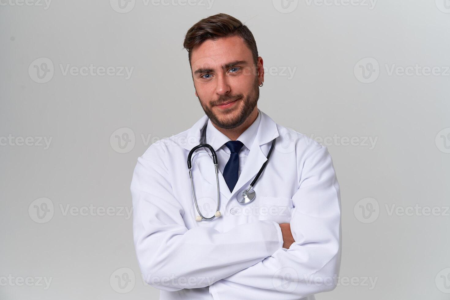 jung gut aussehend modern Arzt im ein Weiß medizinisch Kleid steht im das Studio auf ein Weiß Hintergrund. Schüler Auszubildender von ein medizinisch Universität. foto