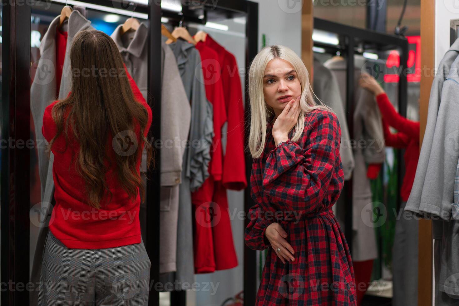 zwei Frauen Freundinnen im ein Mode Boutique wählen ein Mantel zum Herbst Jahreszeit. foto