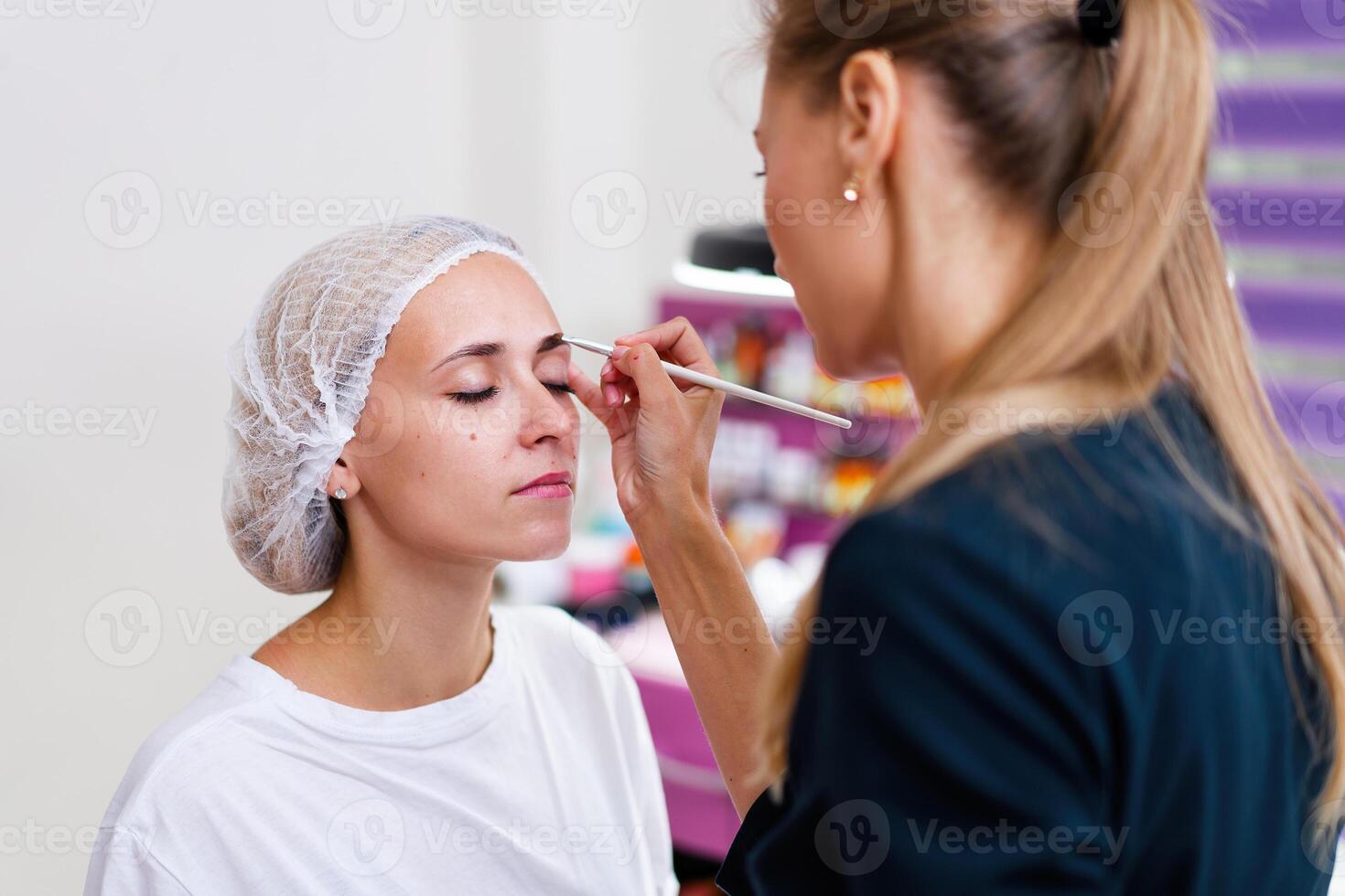 Kosmetologie Kabinett Klient Sitzung auf Couch. Kosmetikerin gilt Markierung auf Augenbrauen. foto
