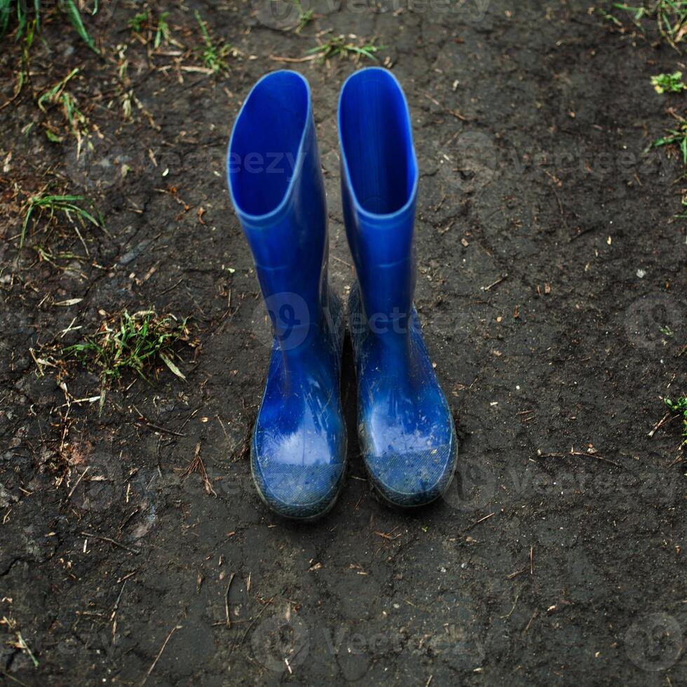 ein Paar von Blau Gummi Stiefel auf ein Schmutz Pfad foto