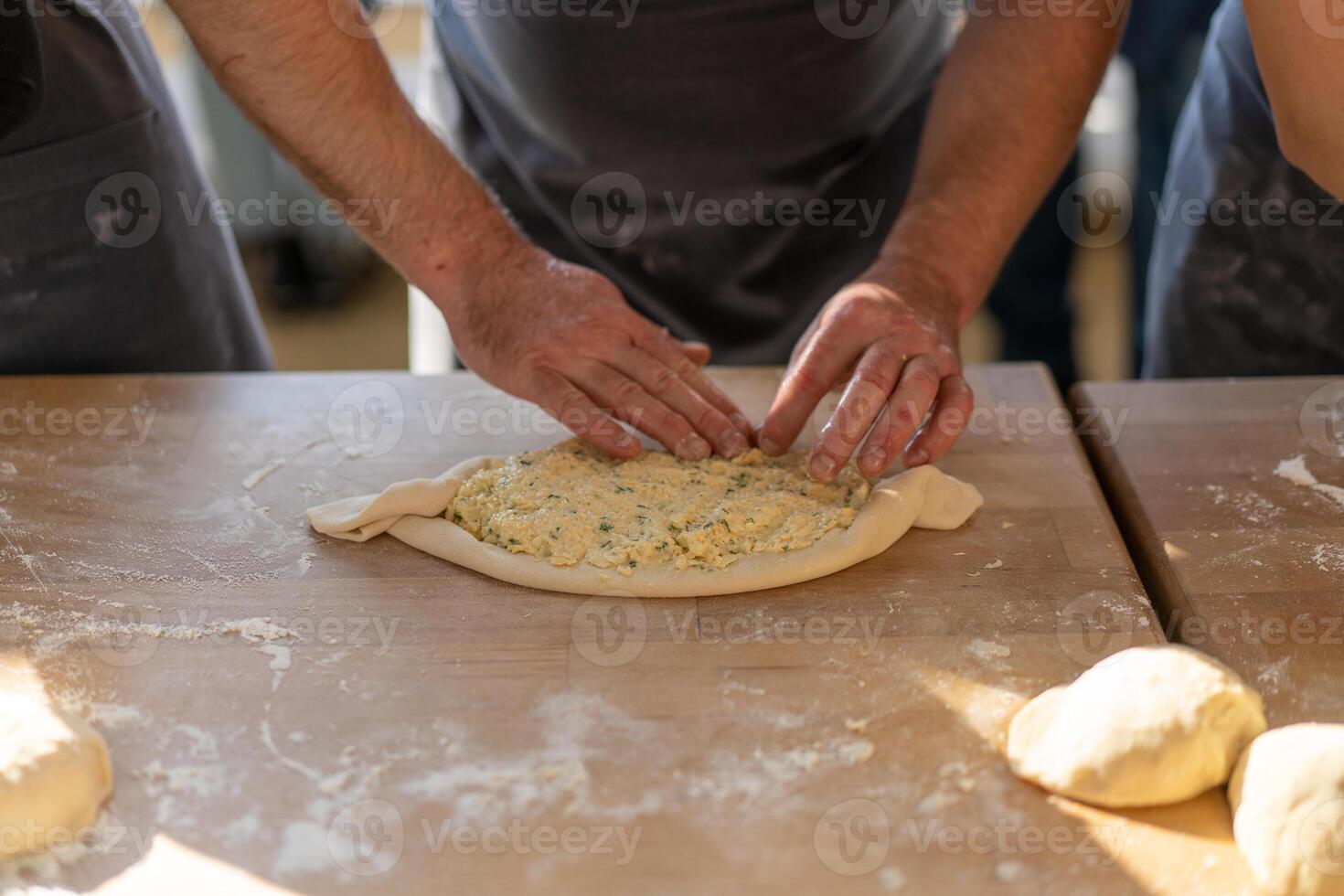 kulinarisch Meister Klasse. Nahansicht von männlich Hände vorbereiten khachapuri. traditionell georgisch Käse Brot. georgisch Essen foto