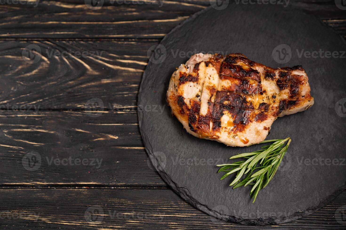 saftig Stück von gebraten Fleisch Lügen auf ein Stein Teller gegen ein schwarz hölzern Tabelle foto