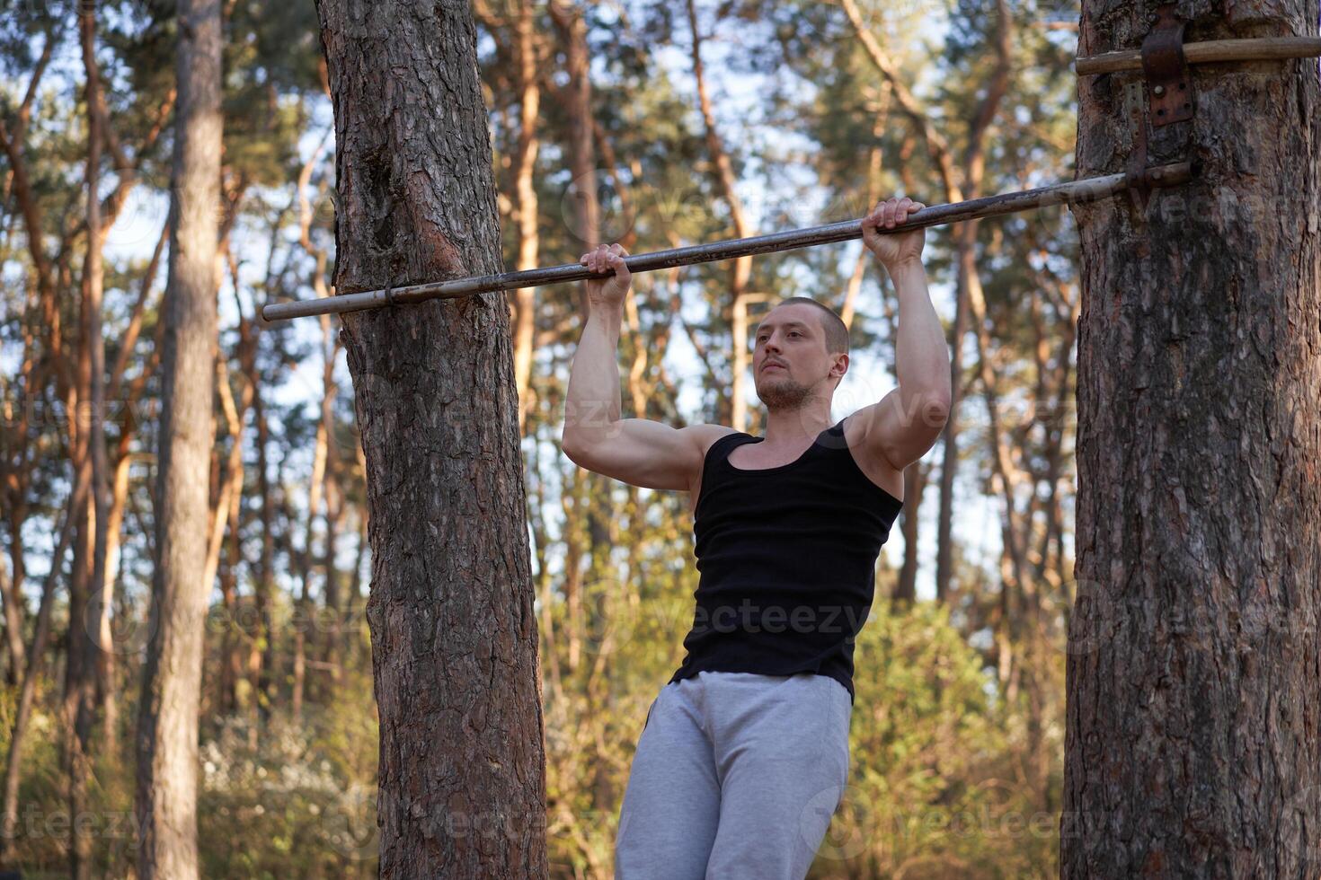 gut aussehend kaukasisch Männer Klimmzug draussen trainieren Kreuz Ausbildung Morgen Pumpen oben Arm ausüben Sport Boden Natur Wald foto