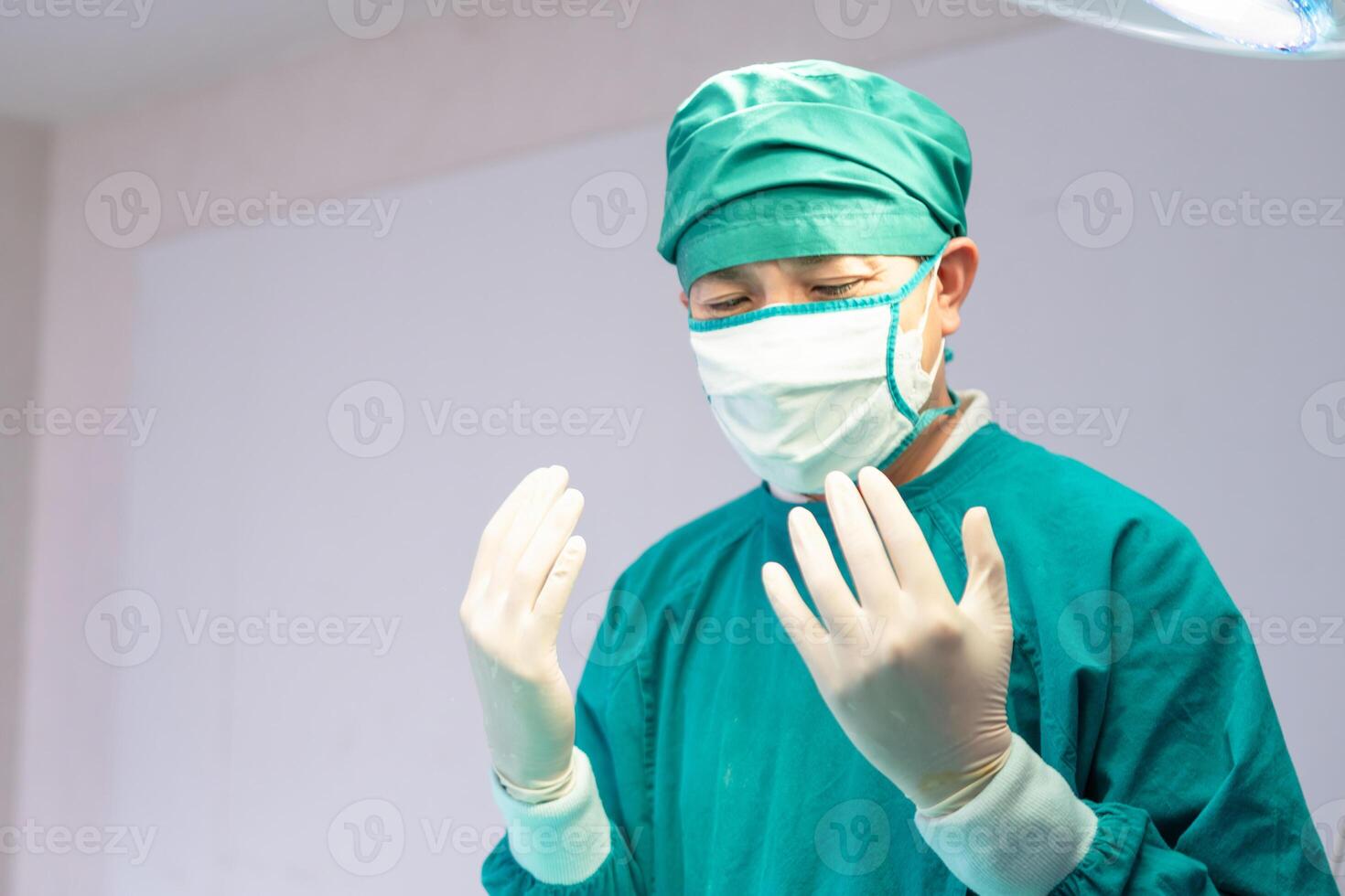 männlicher Chirurg mit medizinischen Schutzhandschuhen und chirurgischer Maske im Operationssaal im Krankenhaus, medizinisches Team, das chirurgische Eingriffe im Operationssaal durchführt foto