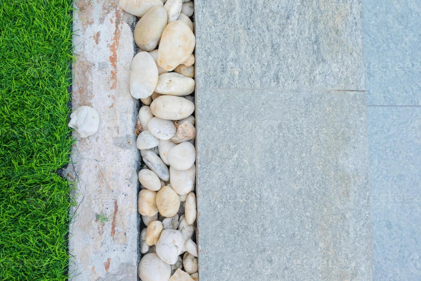 Weiß und braun Stein dekoriert im zwischen Gehweg und Rasen und Fliesen Muster. Landschaft Design Detail. foto