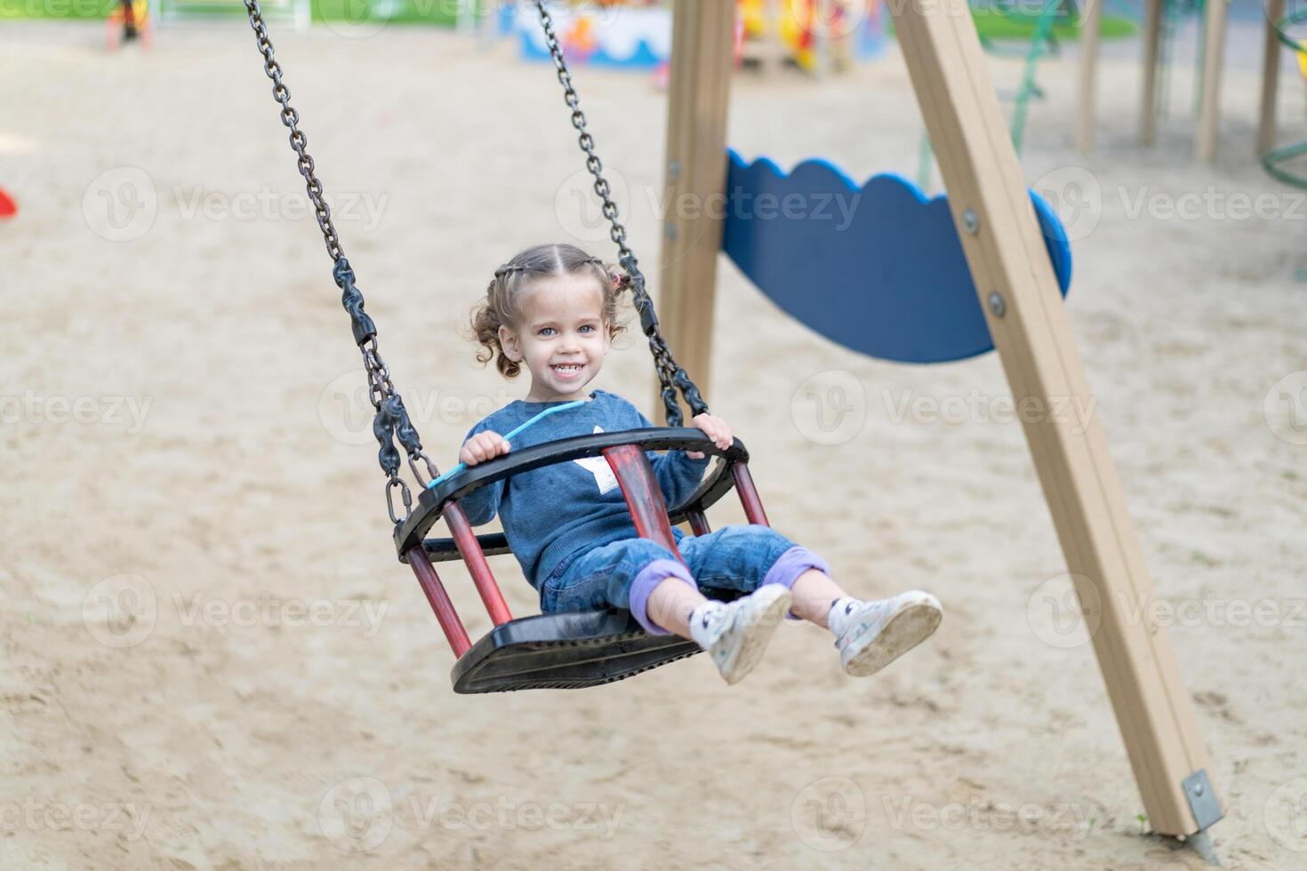 wenig kaukasisch Mädchen Reiten schwingen beim Spielplatz sonnig Sommer- Tag. foto