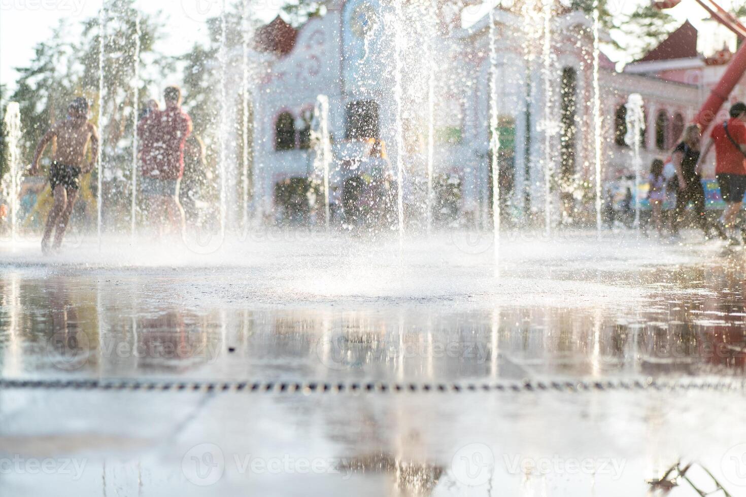 unkenntlich glücklich Kinder haben Spaß spielen im Stadt trocken Wasser Brunnen auf heiß Sommer- Tag foto