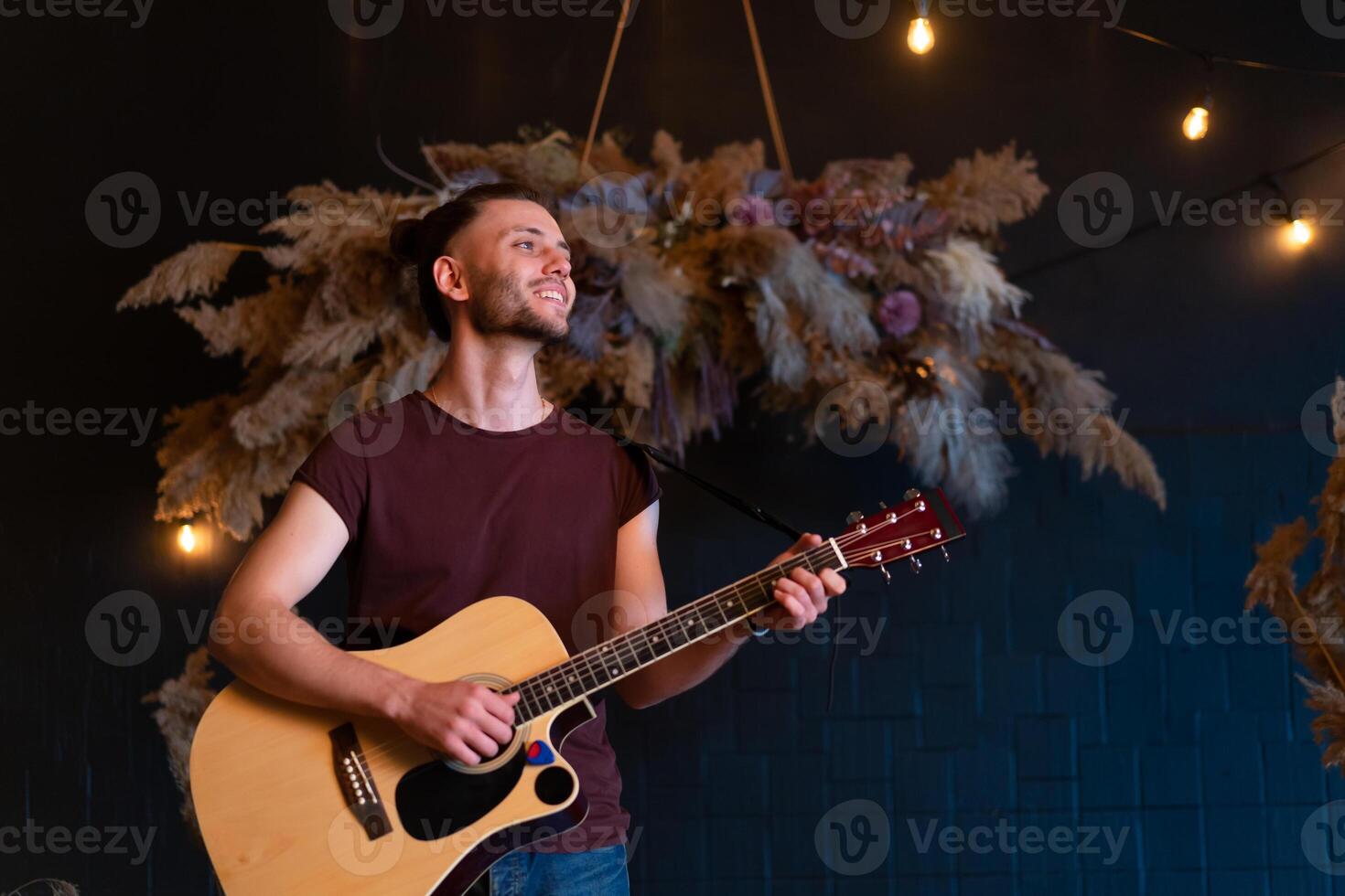 männlich Musiker spielen akustisch Gitarre. Gitarrist Theaterstücke klassisch Gitarre auf Bühne im Konzert foto