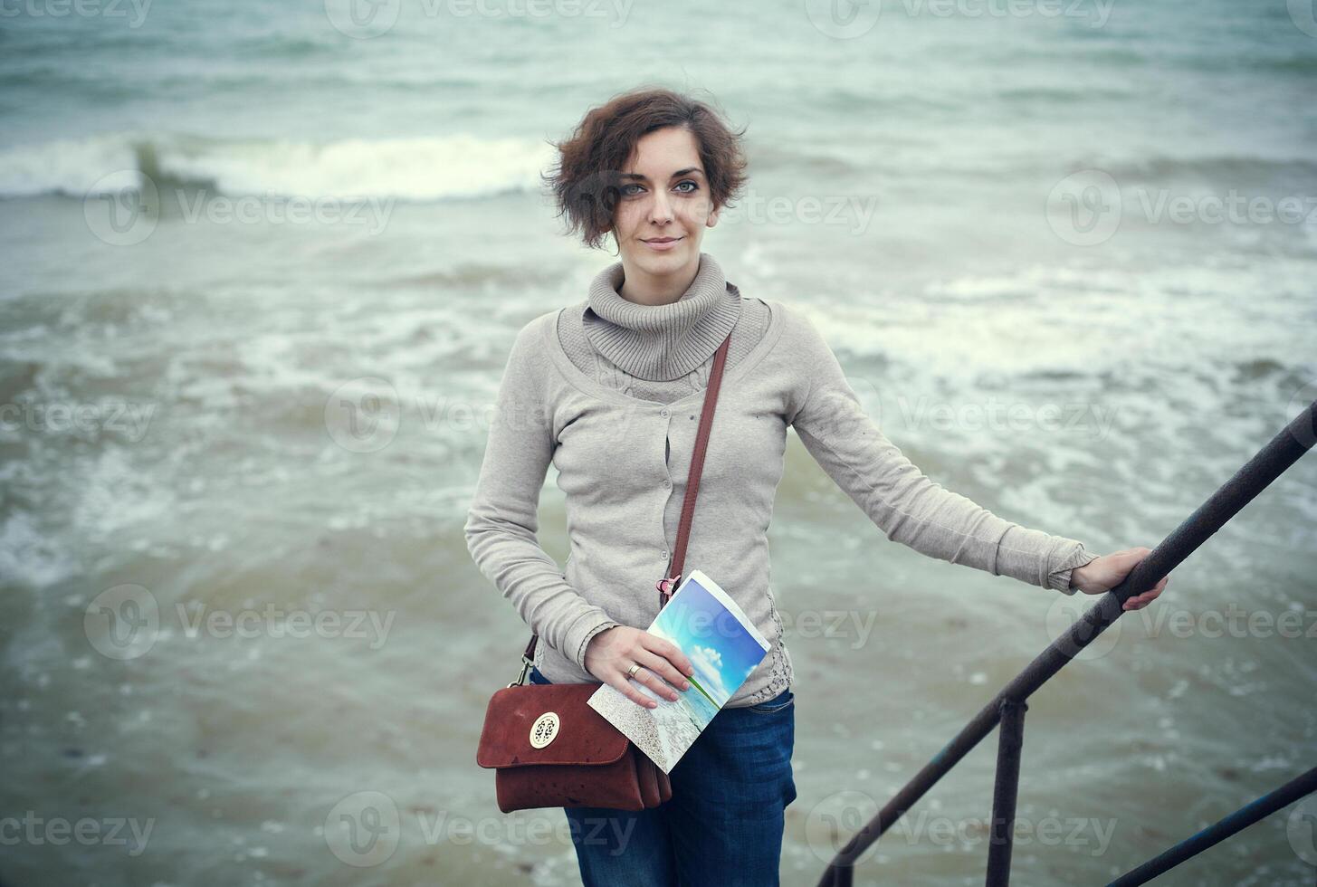 glamourös Porträt von das jung schön Frau im Leder Stiefel auf das Bank von ein Strand foto