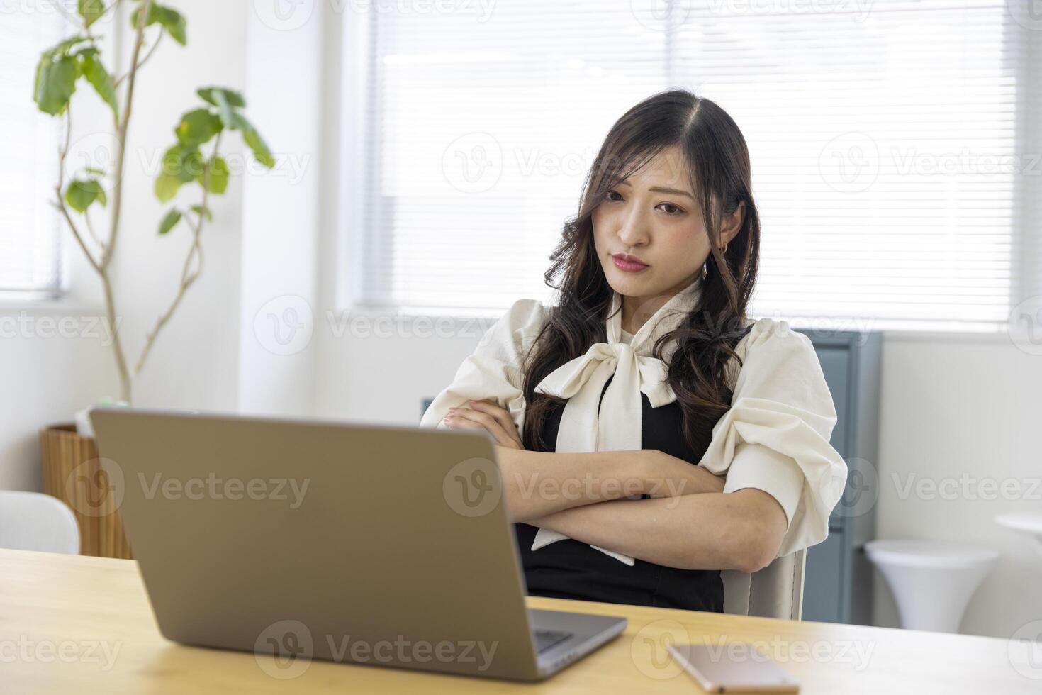 ein besorgt japanisch Frau durch Fernbedienung Arbeit im das klein Büro foto