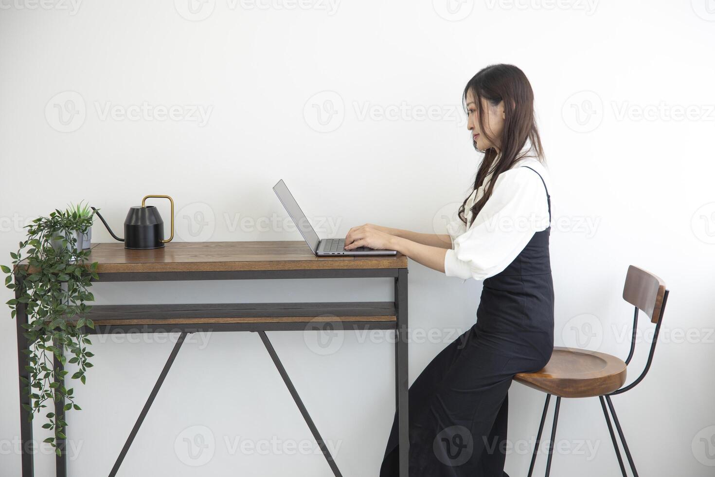 ein japanisch Frau Überprüfung Smartphone durch Fernbedienung Arbeit im das Zuhause Büro foto