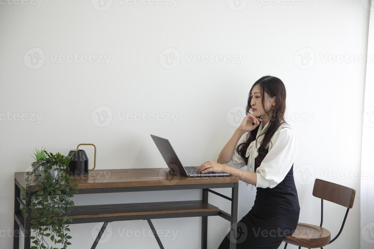 ein japanisch Frau Überprüfung Smartphone durch Fernbedienung Arbeit im das Zuhause Büro foto