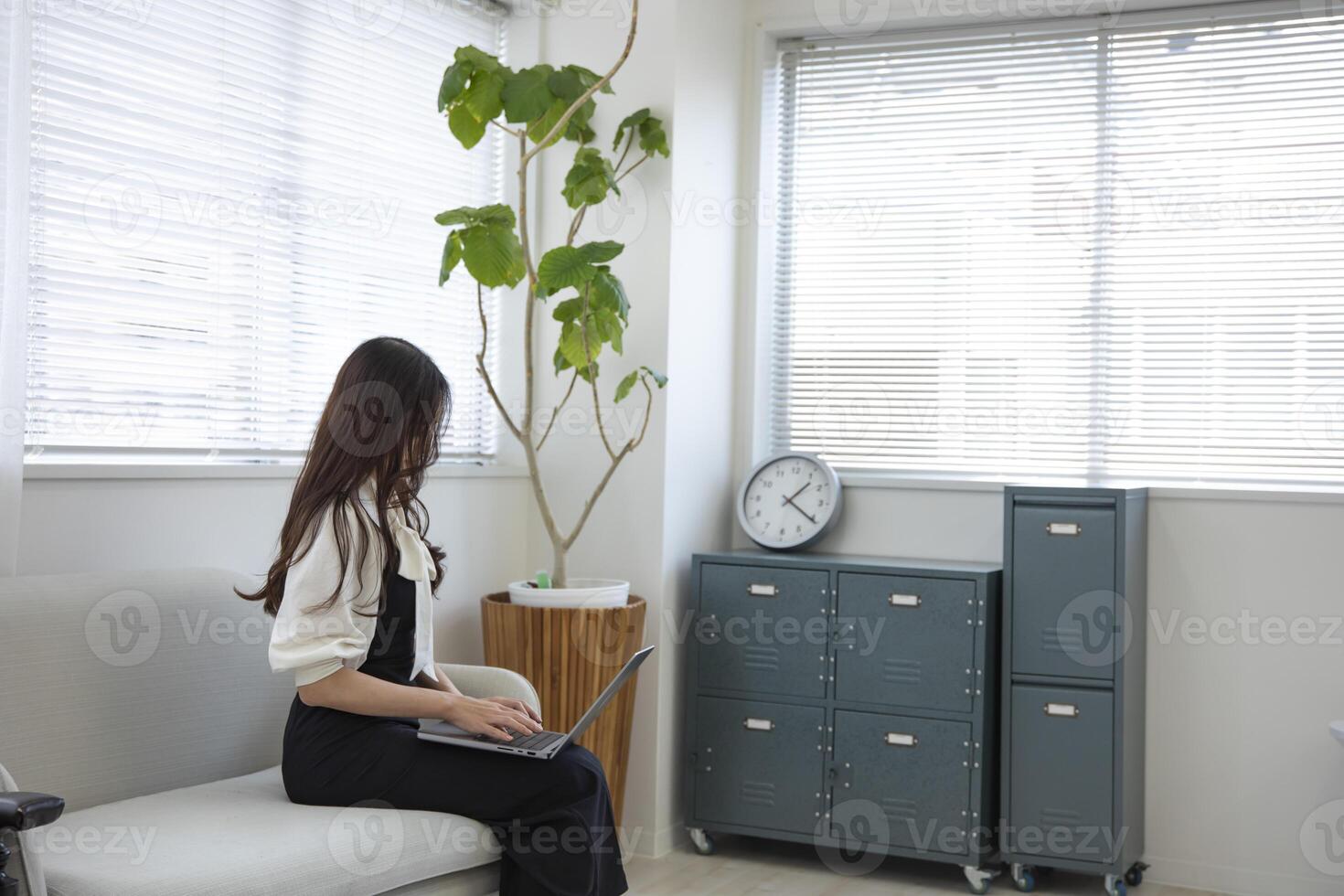 ein japanisch Frau Überprüfung Smartphone durch Fernbedienung Arbeit im das Zuhause Büro foto