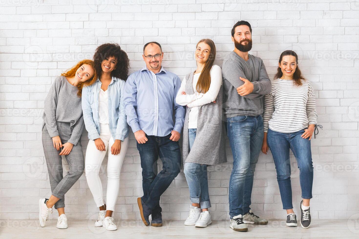 Unternehmen von vielfältig Männer und Frauen Stehen beim Weiß Backstein Mauer foto