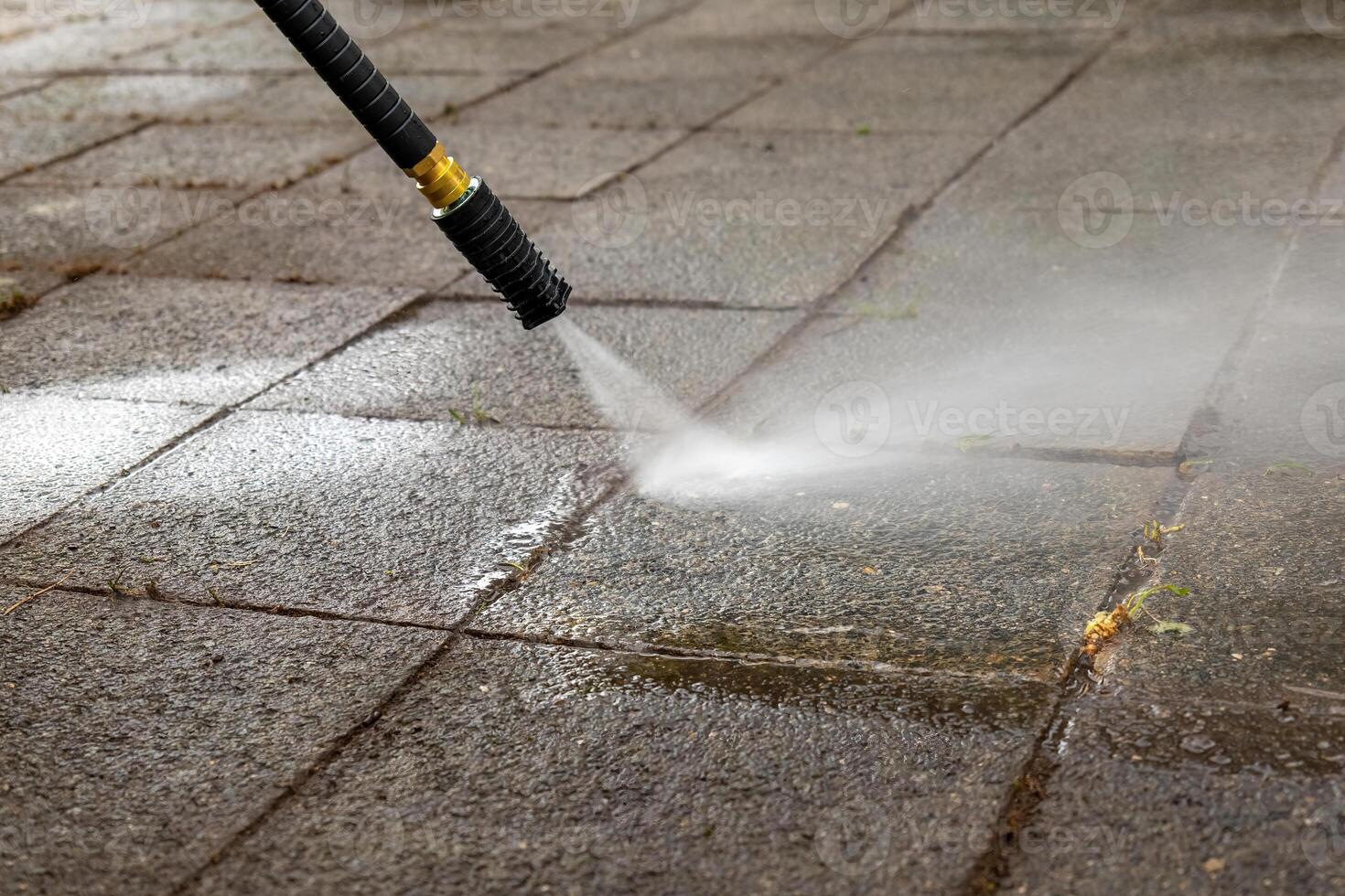 Druck Unterlegscheibe ist Sprühen Wasser auf ein schmutzig Bürgersteig foto