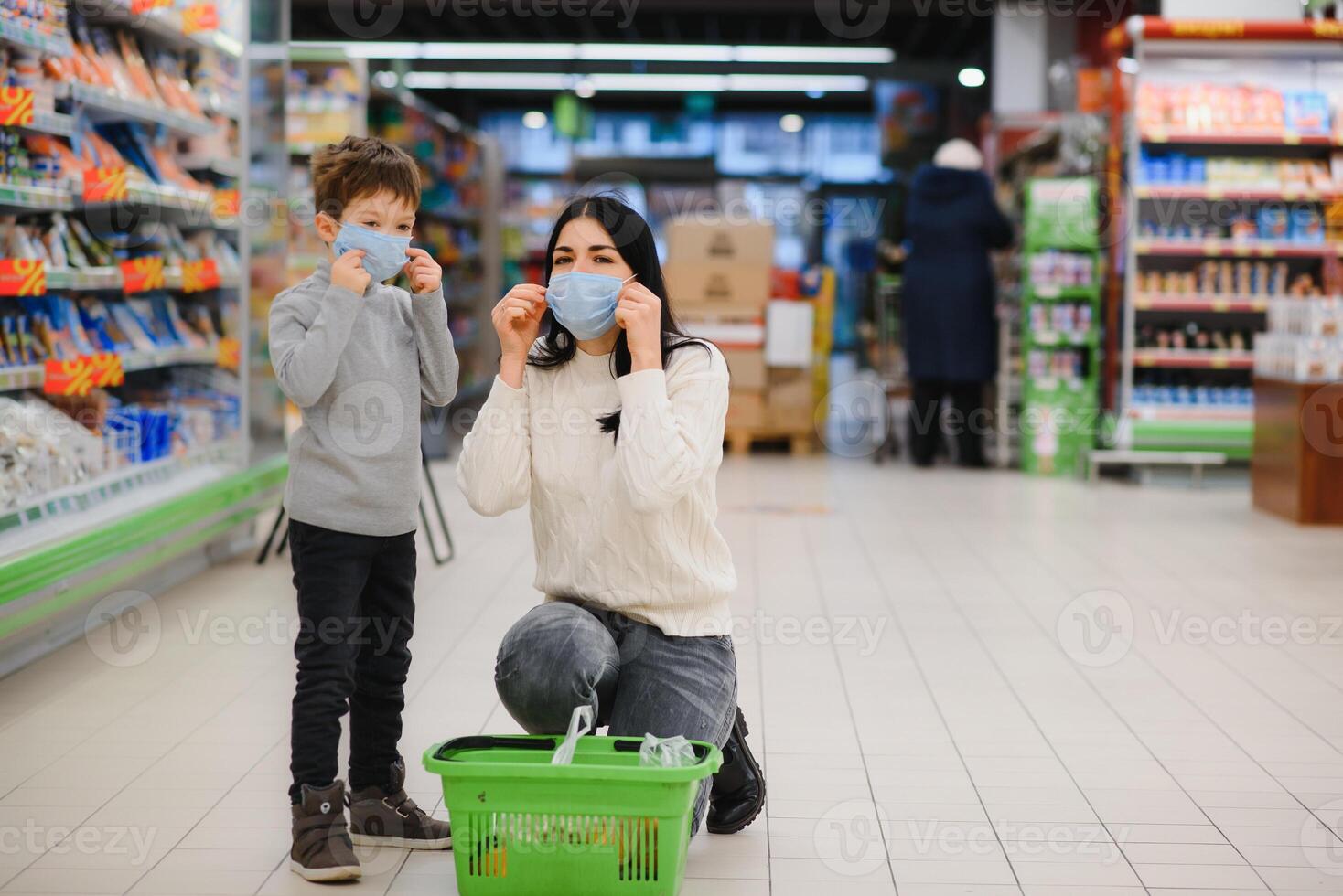 jung Frau und ihr Kind tragen schützend Gesicht Masken Geschäft ein Essen beim ein Supermarkt während das Coronavirus Epidemie oder Grippe Ausbruch. foto