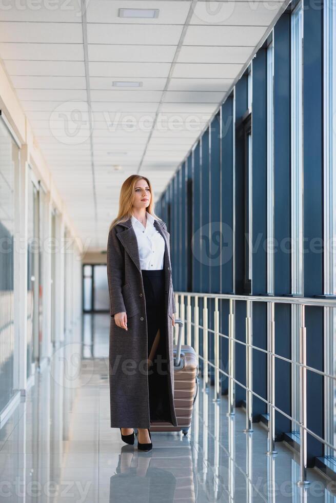 attraktiv jung Frau mit Reise Koffer Stehen auf zweite Fußboden von Flughafen warten Zimmer Lager Foto