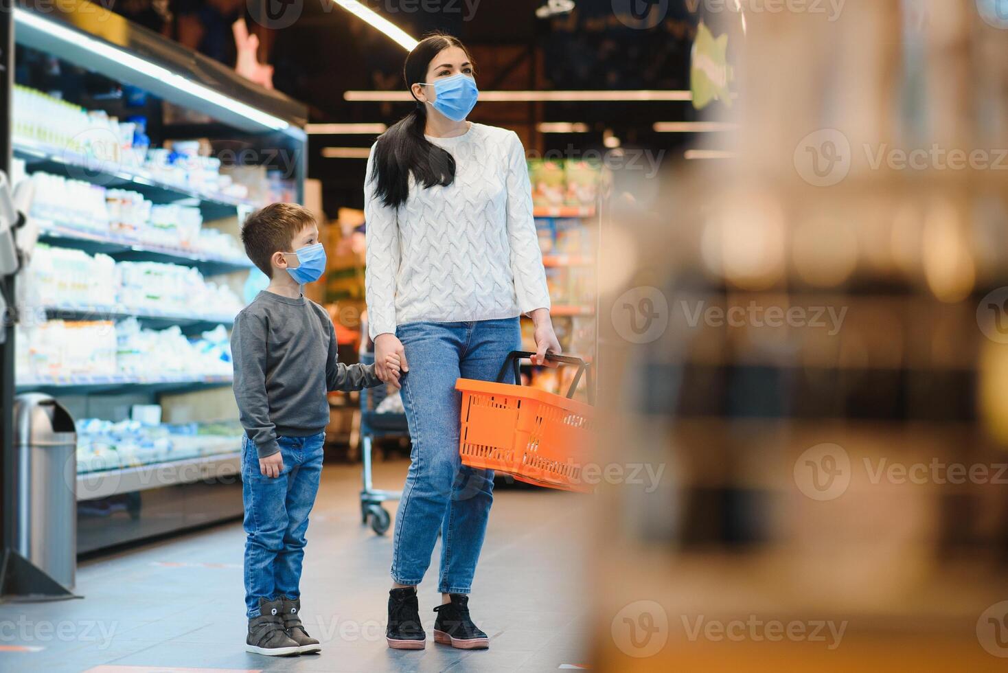 jung Frau und ihr Kind tragen schützend Gesicht Masken Geschäft ein Essen beim ein Supermarkt während das Coronavirus Epidemie oder Grippe Ausbruch. foto