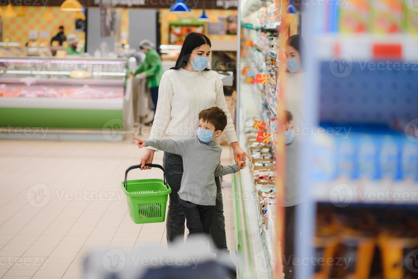 Porträt von ein Mutter und ihr wenig Sohn tragen schützend Gesicht Maske beim ein Supermarkt während das Coronavirus Epidemie oder Grippe Ausbruch. leeren Raum zum Text foto