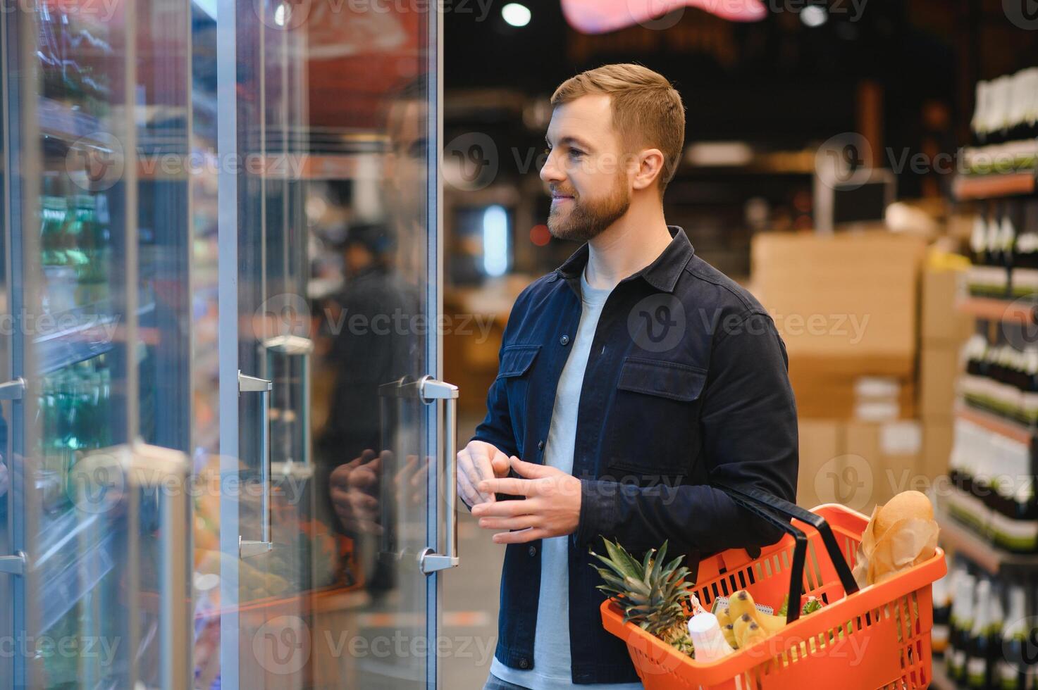 Kunde im Supermarkt. Mann tun Lebensmittelgeschäft Einkaufen Stehen mit Wagen wählen Essen Produkt drinnen. Kerl Kauf Lebensmittel im Essen speichern. selektiv Fokus, Kopieren Raum. foto